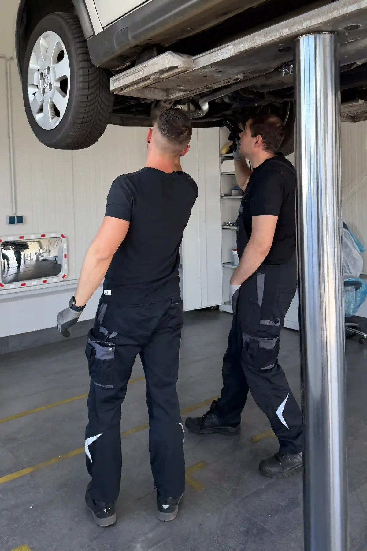Zwei Mechaniker arbeiten an einem Fahrzeug auf der Hebebühne