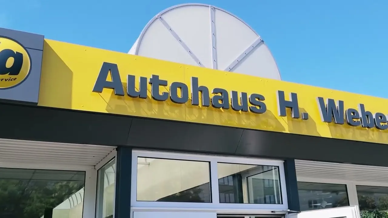 Der gelbe Schriftzug Autohaus H. Weber über der Glasfront, links das Logo von 1a Autoservice
